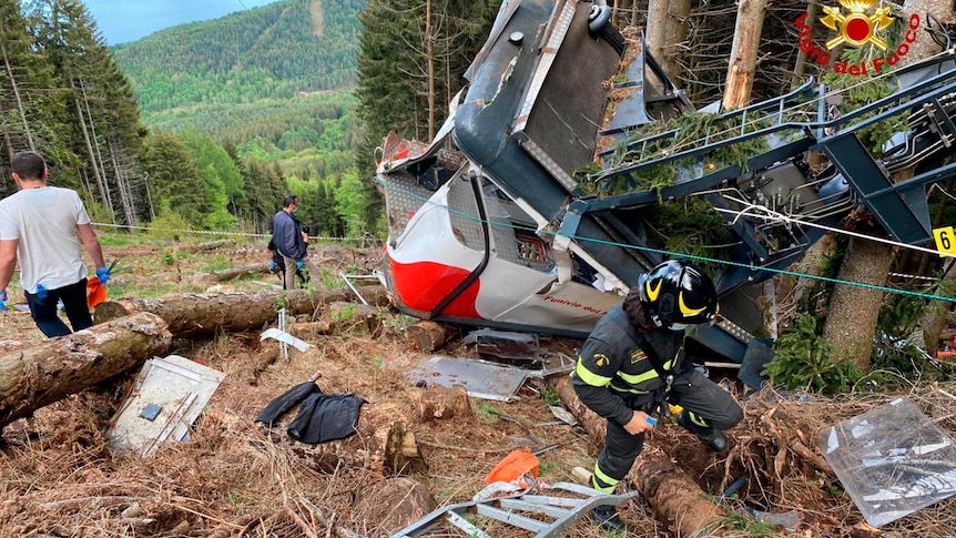 The shattered remains of a cable car in a clearing on the side of a mountain.