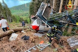 The shattered remains of a cable car in a clearing on the side of a mountain.