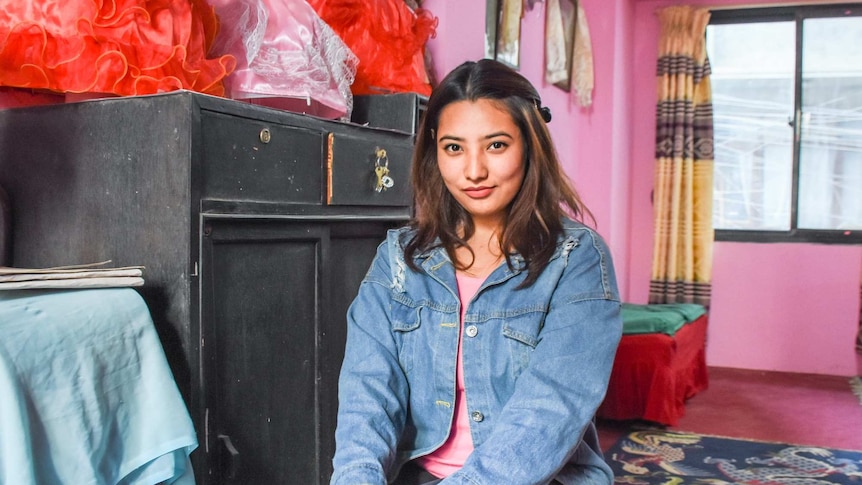 A smiling young woman in a pink room