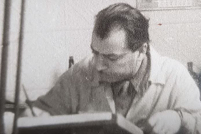 An old photo shows Iwan Iwanoff leaning over a desk holding a pencil or pen.
