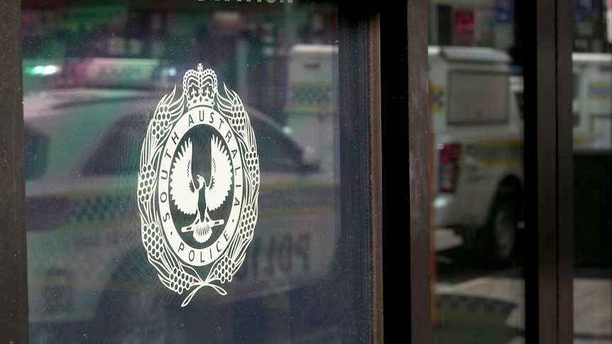 The logo of SA Police on the glass window of a police station.