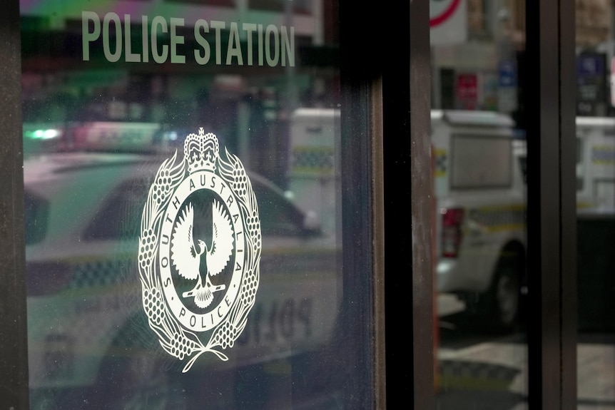 The logo of SA Police on the glass window of a police station.