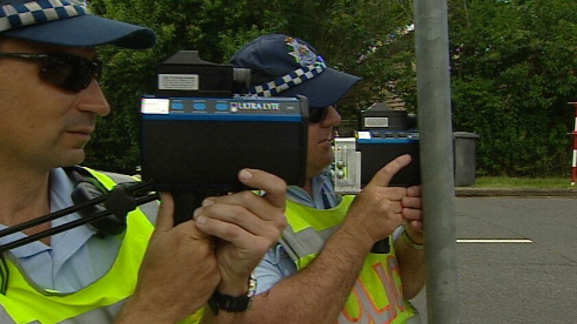 TV still of two Qld traffic police pointing their radar guns at oncoming cars.