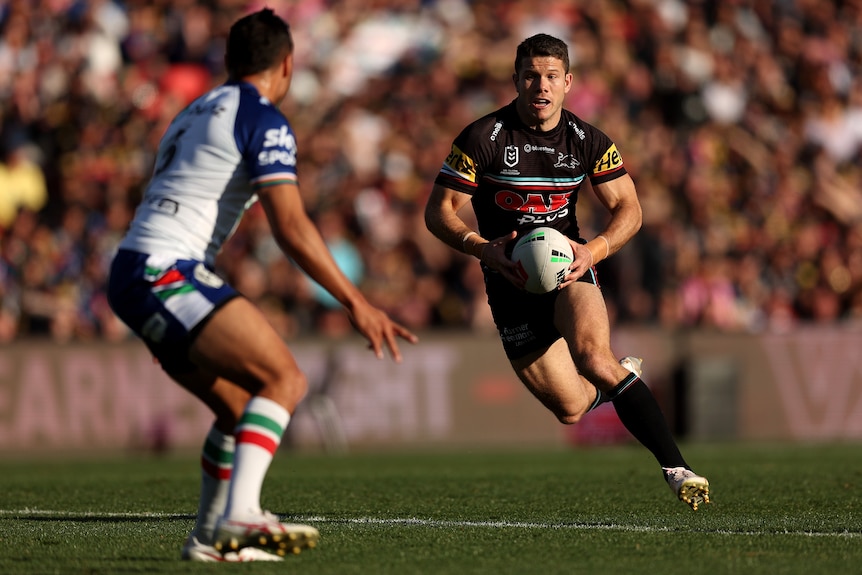 A Penrith Panthers NRL player runs with the ball, preparing to step a defender as he tries to break downfield. 