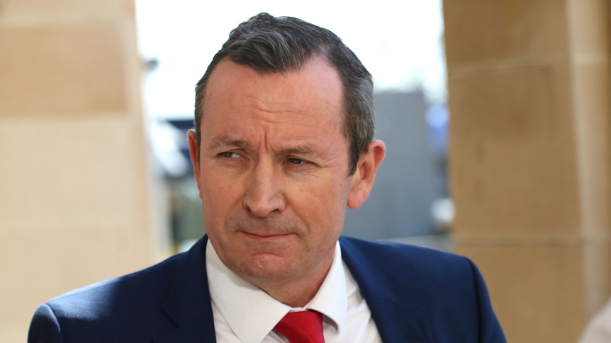 Mark McGowan wears a serious expression and a navy blazer and red tie