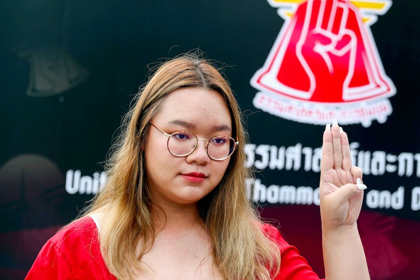 A young Thai woman holding up three fingers