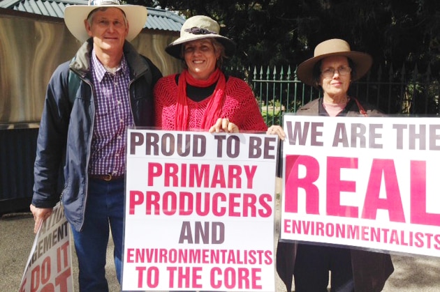 Farmers hold up protest signs