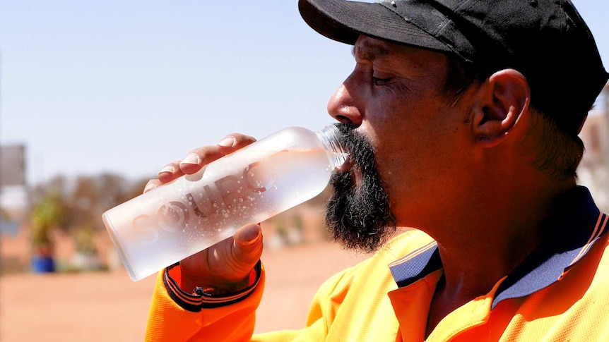 Man in orange shirt drinking from water bottle