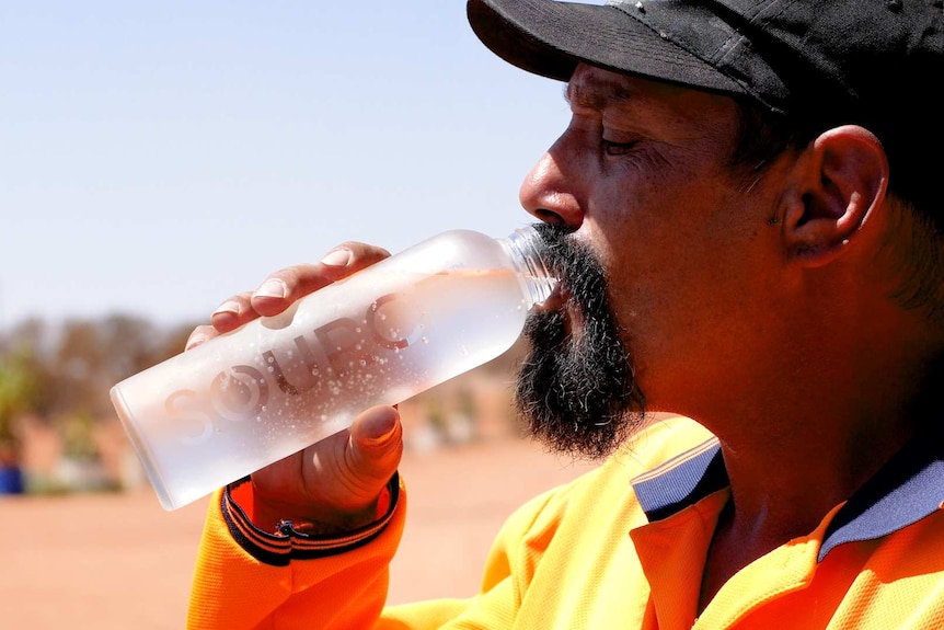 Man in orange shirt drinking from water bottle