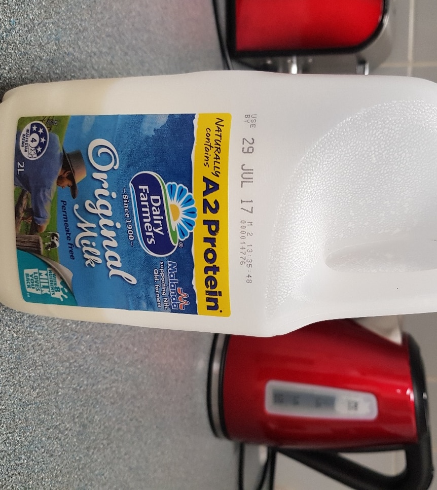 A half empty two-litre bottle of milk, showing Malanda brand on a kitchen benchtop