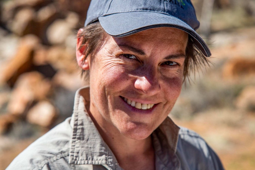 Claire Drabsch is outdoors, smiling in a cap