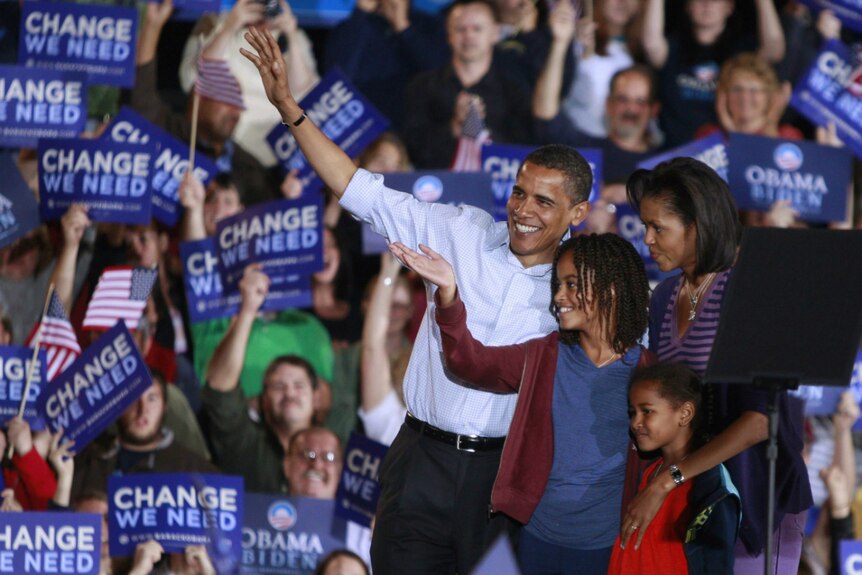 Barack Obama waves to supporters on stage with his wife Michelle and daughters Malia and Sasha.