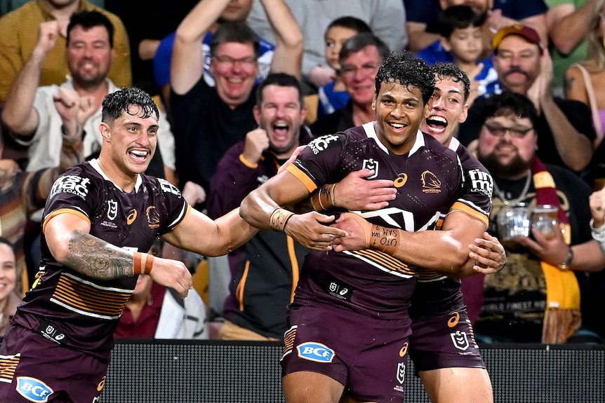 Brisbane Broncos player Selwyn Cobbo (centre) is hugged by Jordan Riki (right). Kotoni Staggs is there too.