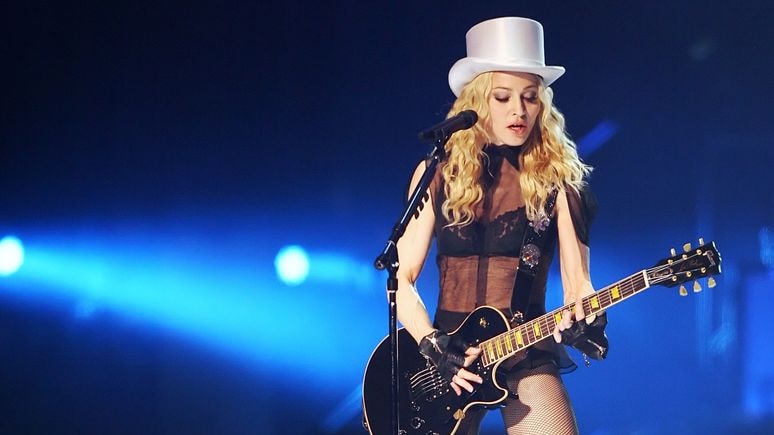 Madonna performs with a guitar onstage