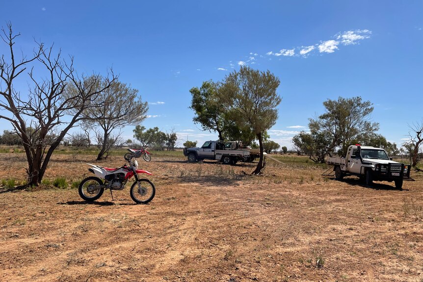 Motorbikes and utilities parked in outback landscape 