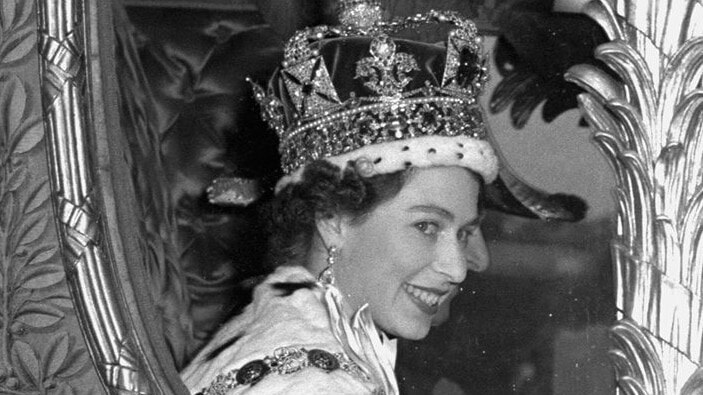 Queen Elizabeth II smiles through the window of a coach after her coronation in 1953, shortly after the death of her father King George VI.