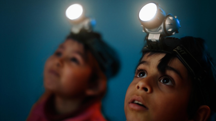 Two children with head torches looking up