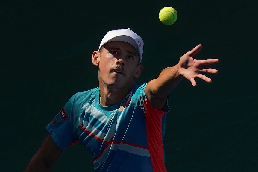 The light focuses on the face of a tennis player who is eyeing the ball as he serves at the US Open.