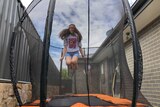 Samantha is airborne and can be seen through the netting of the trampoline.