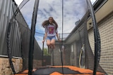 Samantha is airborne and can be seen through the netting of the trampoline.