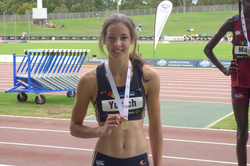 A young girl named Alanah Yukic stands with a medal after winning a race.