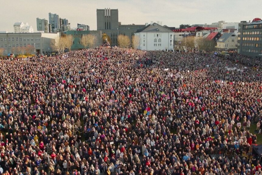 A crowd of people protest in a square in Iceland.