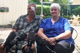 Retired miner Percy Verrall has one eye patched and sits before microphones beside his wife Daphne in their backyard