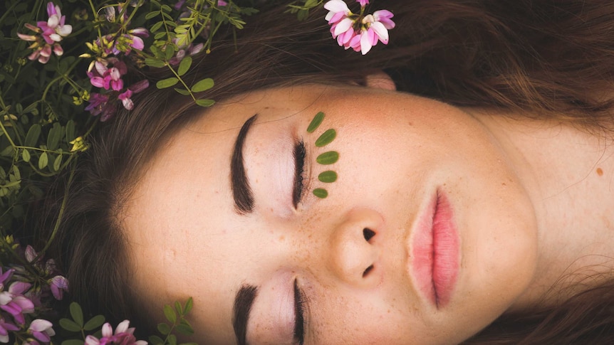 Woman lying in the grass with face paint