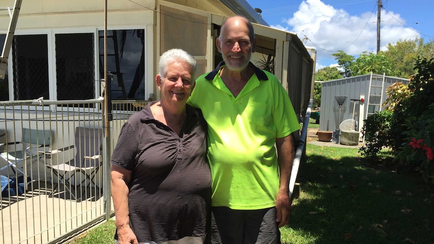 Bev and Bill Hall stand arm-in-arm alongside their house that had to be almost completely rebuilt after Cyclone Yasi.