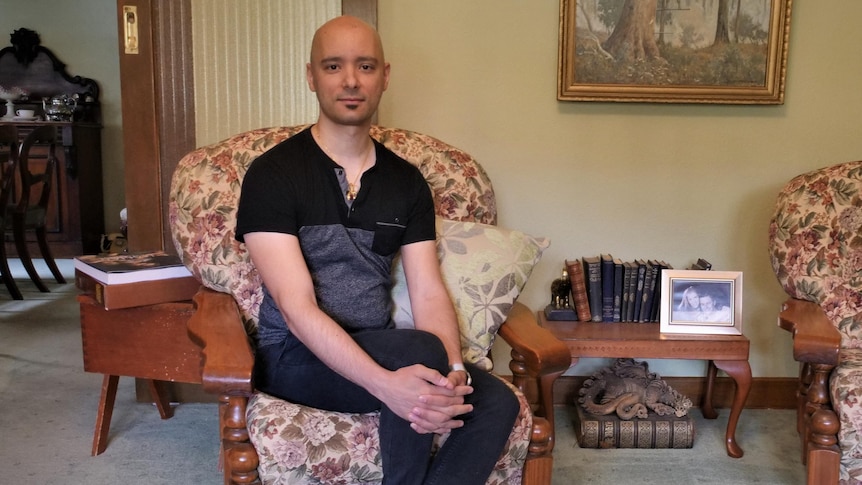 A man sits on an arm chair in a lounge room