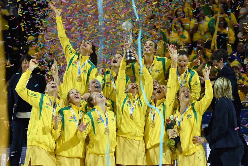 The Diamonds hold up the Netball World Cup trophy as confetti falls.