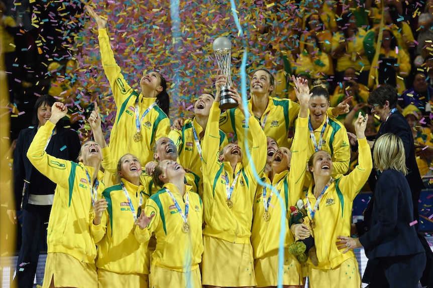 The Diamonds hold up the Netball World Cup trophy as confetti falls.