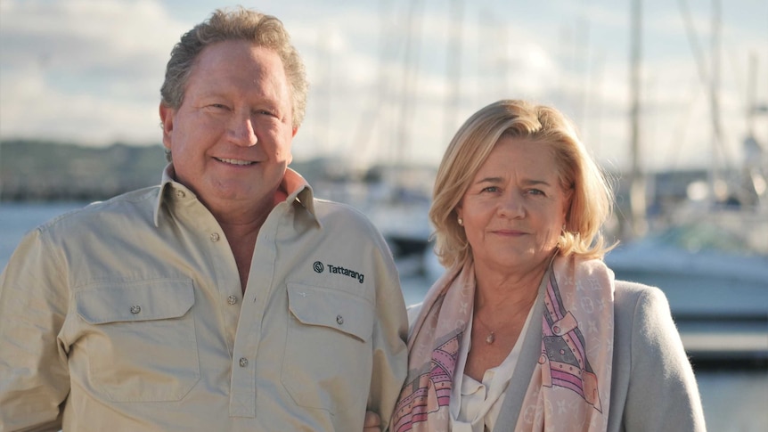 A man and a woman standing next to each other with boats in the background