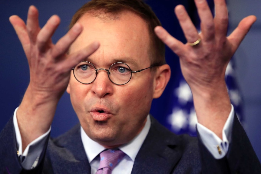 A head-and-shoulders shot shows Mick Mulvaney with his hands in the air