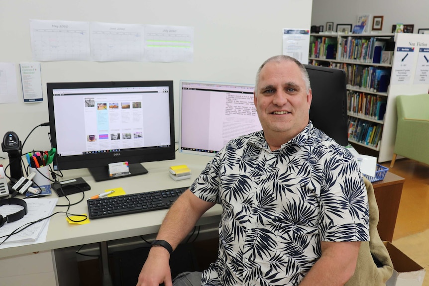 A man sits smiling in front of his computer.