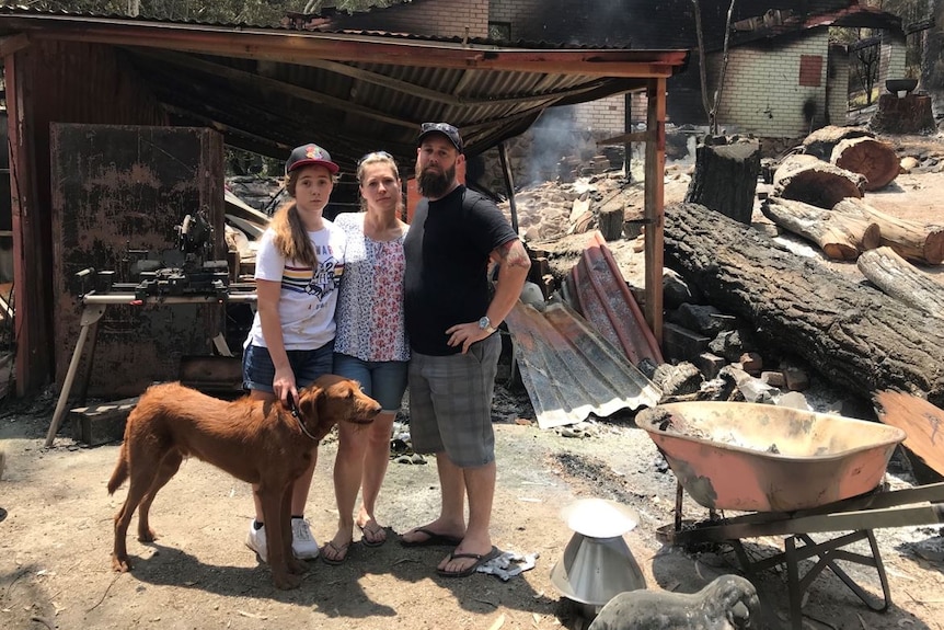 Marc, Rhiann and Estelle Webb stand in front of rubble