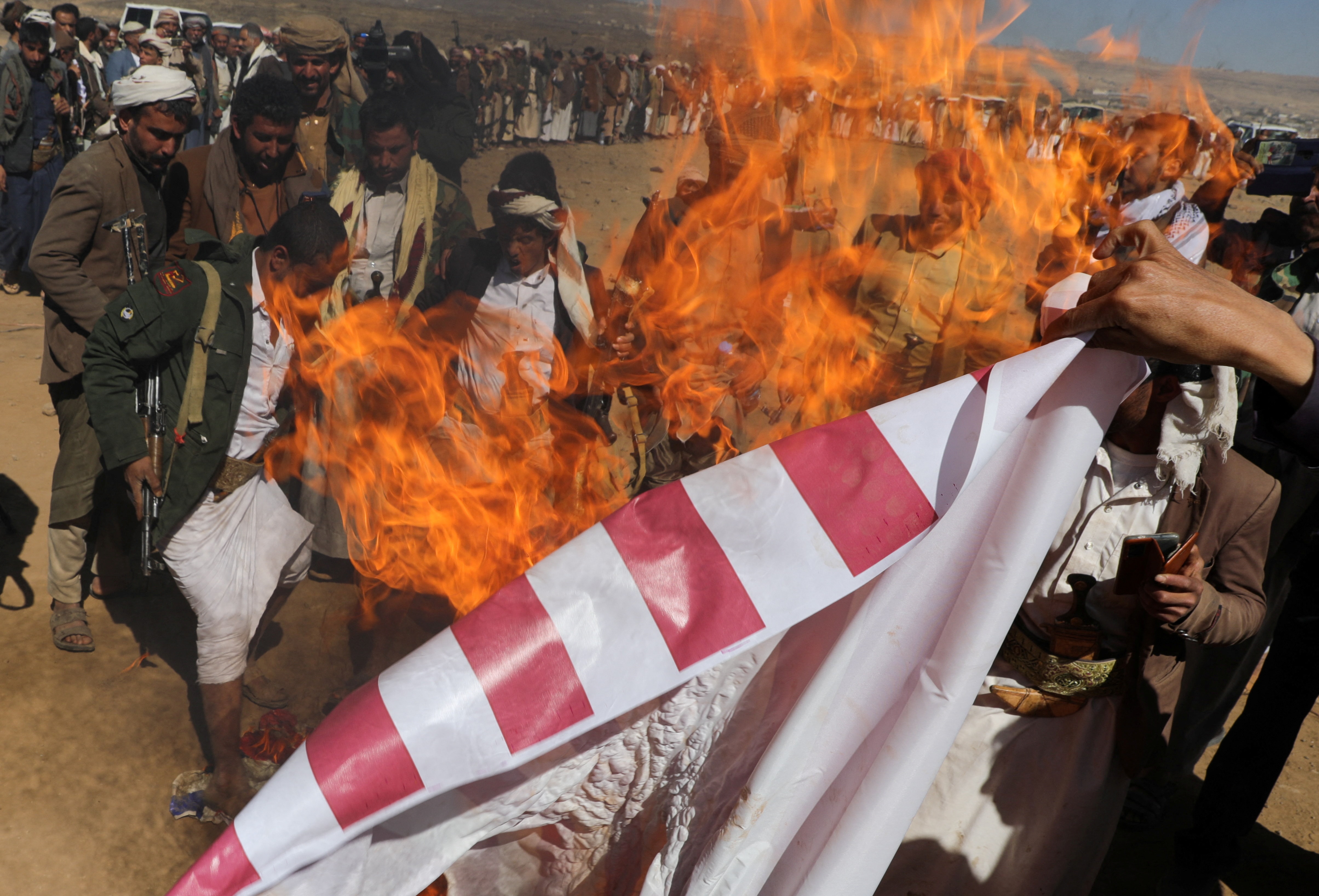 Flames engulf US flag held up in sand 