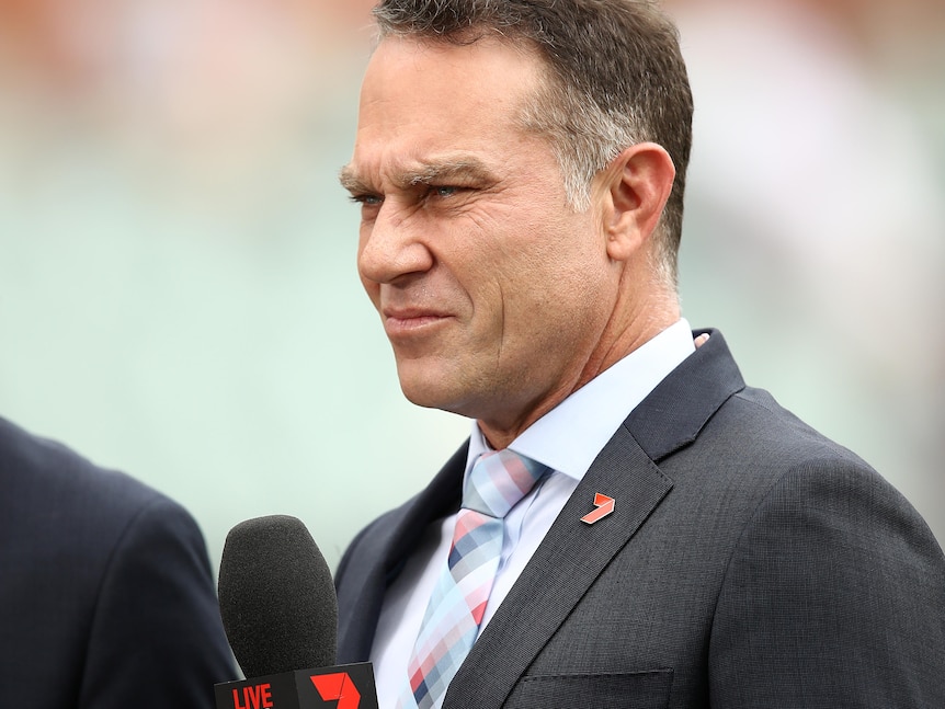 Sports commentator standing with a microphone in his hands during a live broadcast 