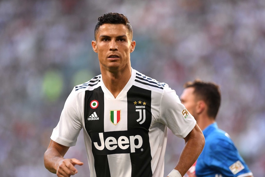 Cristiano Fonaldo faces the camera wearing a white jersey with black stripes.