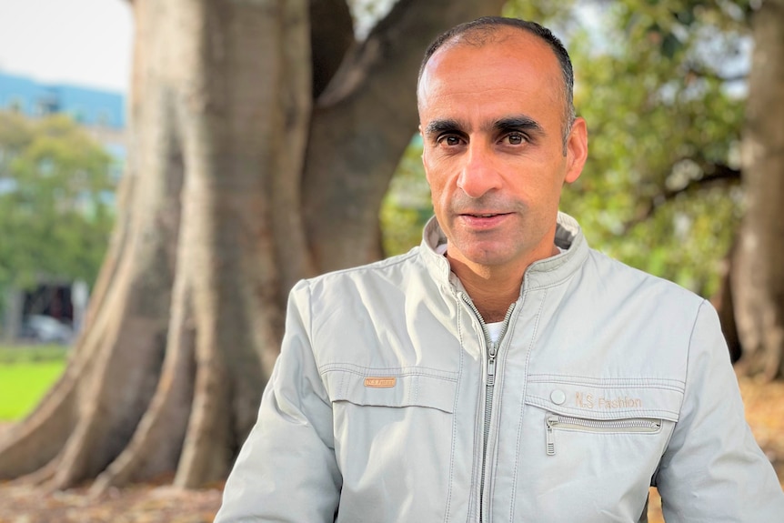 A man sitting with trees in the background