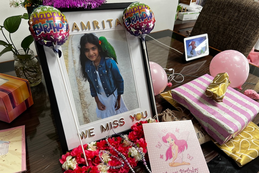 A photo frame of a little girl surrounded by cards and balloons.