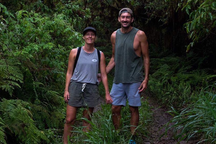 A couple stand in a jungle.