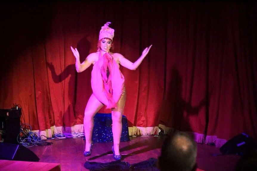 A performer on stage wears a costume shaped like a large vagina.
