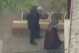 Aerial news footage shows Cardinal Pell being ushered inside the a church property in Melbourne by a nun.