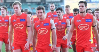 Gold Coast players look downcast as they leave the field