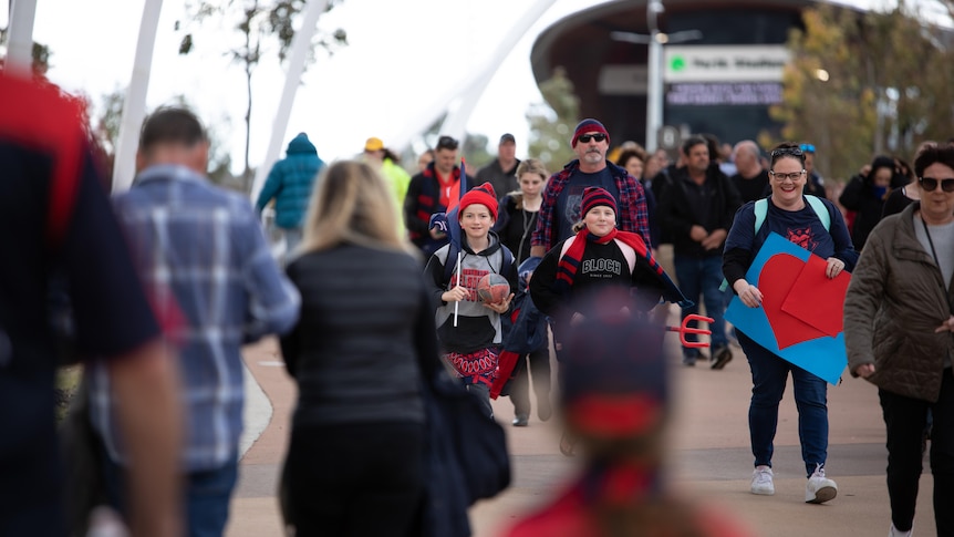 Two children supporting the Melbourne football club walk into Perth Stadium.