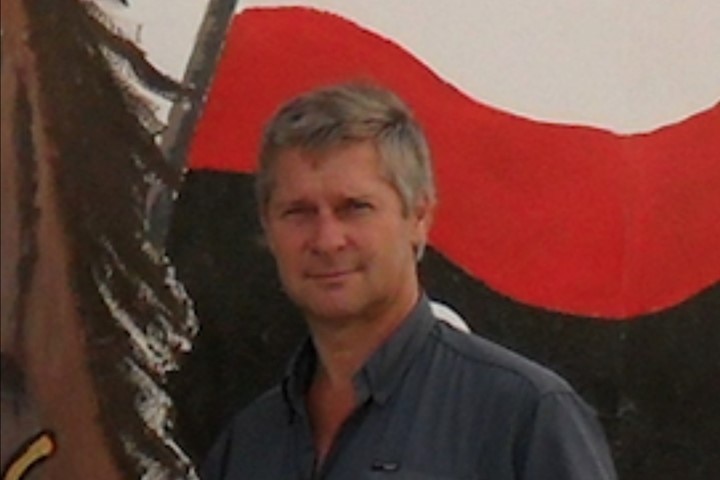 An old photo of an older man with grey hair in a navy blue shirt