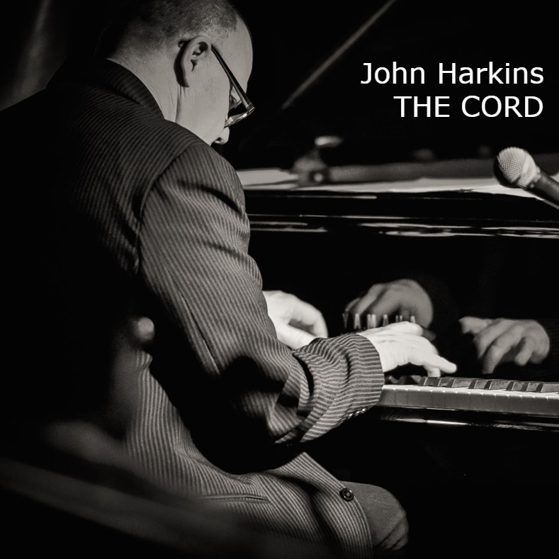 A monochrome shot of John Harkins at the piano
