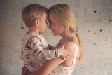 Side view of Ivanka Trump holding her young son, son wearing pyjamas, mother and son's foreheads pressed together, smiling