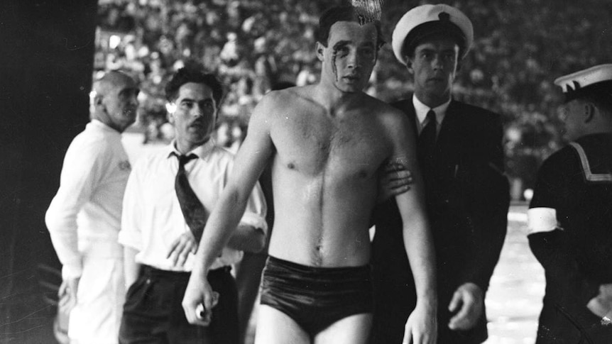 A photo of Hungarian water polo player Ervin Zádor being led away from a swimming pool by officials.